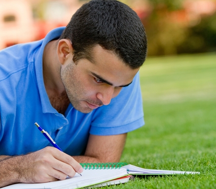 סטודנט כותב על הדשא במחברת